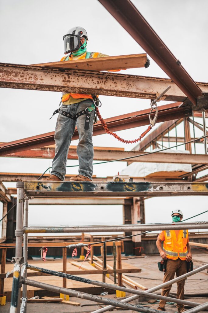 Two construction workers working on the exterior of an apartment building under construction